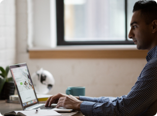 a side angle man smiling in front of his laptop